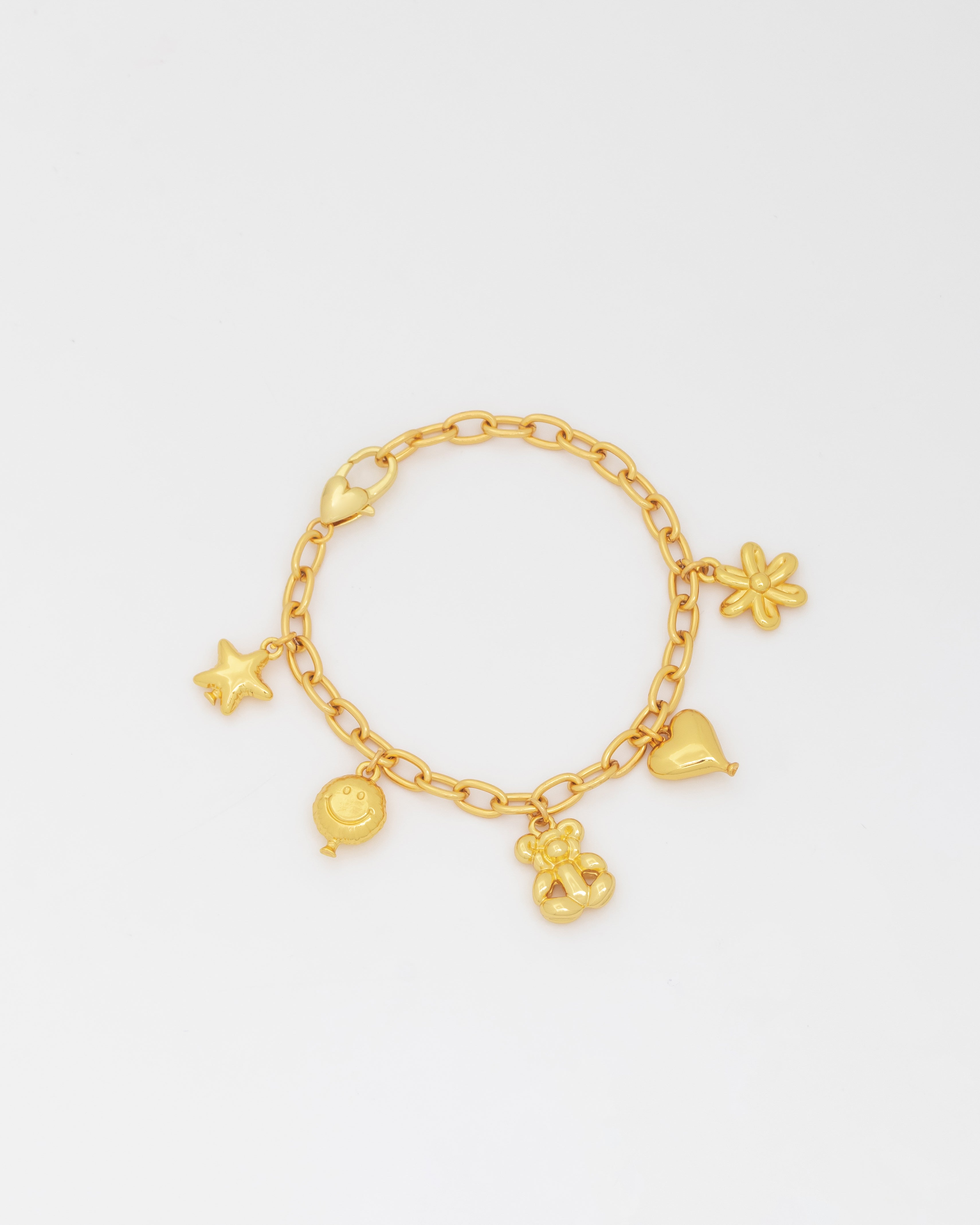 Gold bracelet with various charms on a light gray background