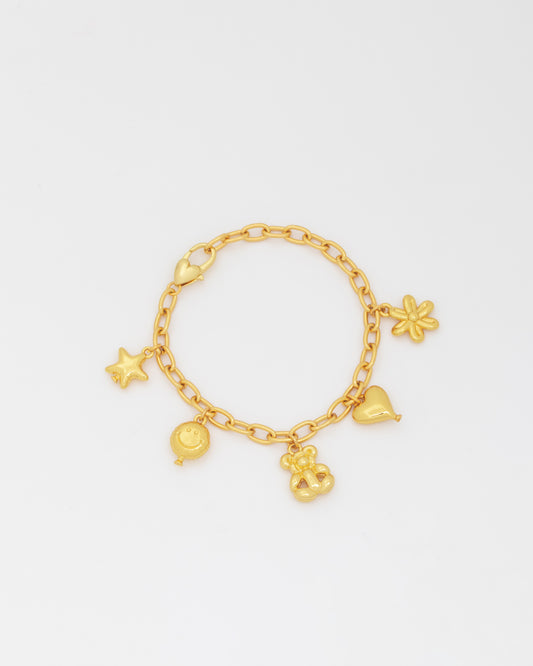 Gold bracelet with various charms on a light gray background