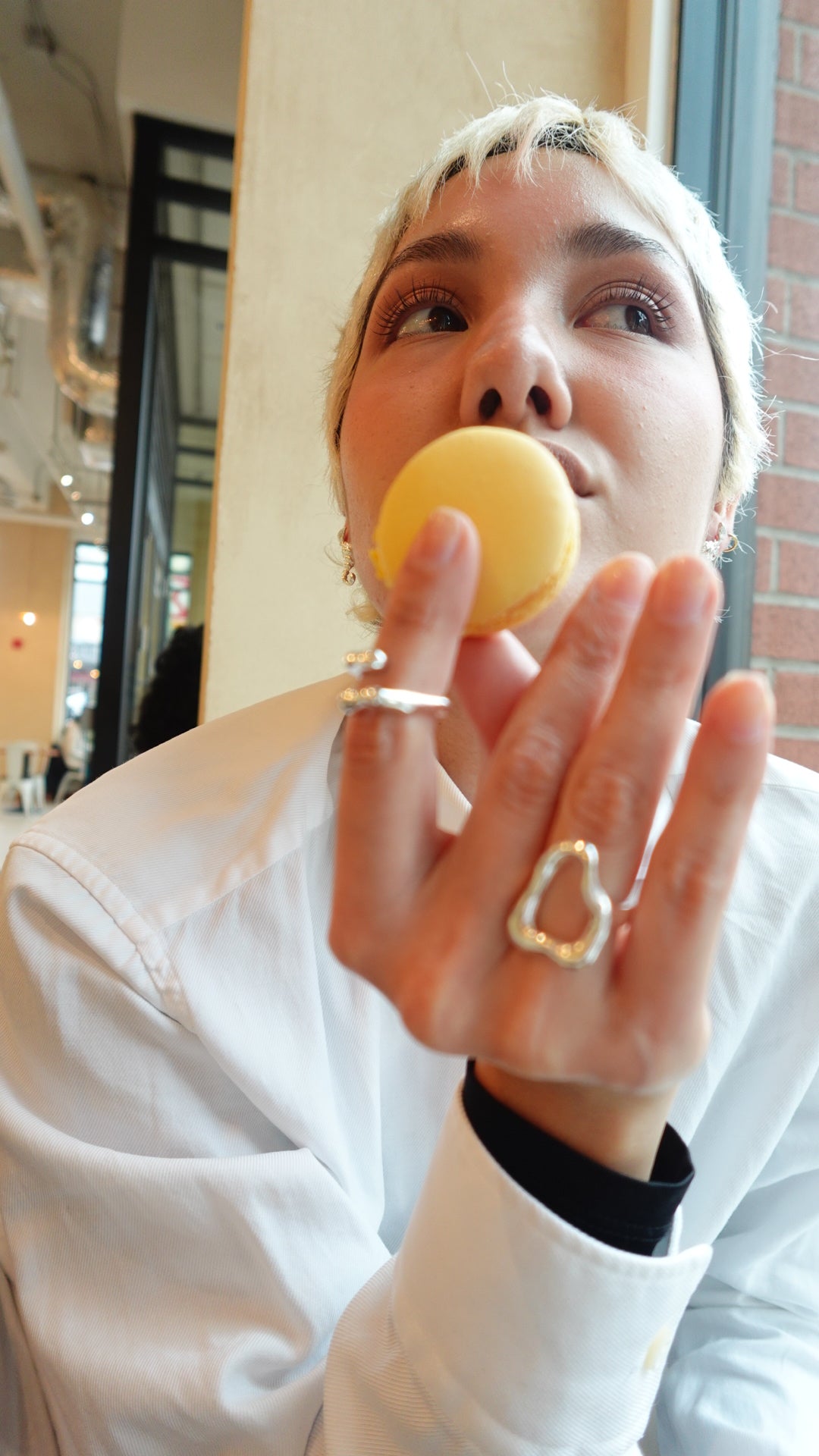 a girl eating macarons with some silver rings, showing the siluet trendy rings